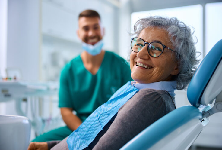 A woman smiles at the dentist after talking with StAK Insurance about understanding dedictibles & maximums